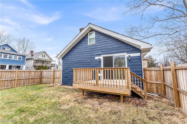 rear view of house with a fenced backyard, a lawn, and a wooden deck