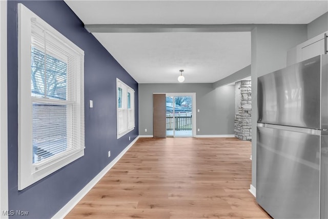 interior space with freestanding refrigerator, white cabinetry, light wood-style flooring, and baseboards