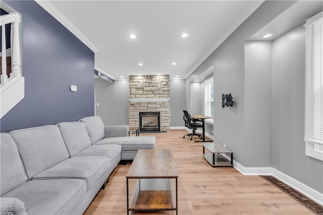 living area with baseboards, ornamental molding, and a stone fireplace