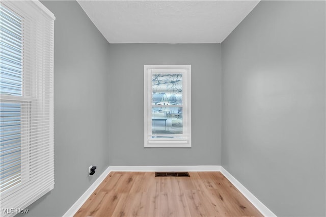 clothes washing area featuring visible vents, light wood-style flooring, and baseboards