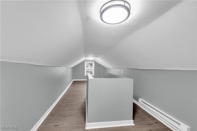 additional living space featuring a baseboard heating unit, vaulted ceiling, baseboards, and wood finished floors