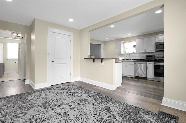 kitchen featuring dark countertops, dark wood-style floors, a healthy amount of sunlight, and appliances with stainless steel finishes