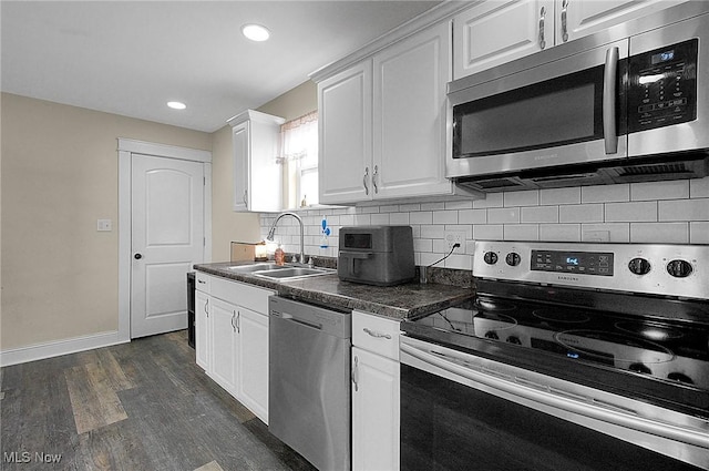 kitchen with dark countertops, white cabinetry, appliances with stainless steel finishes, and a sink