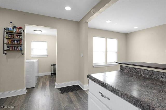 interior space featuring dark wood-type flooring, dark countertops, white cabinets, and baseboards