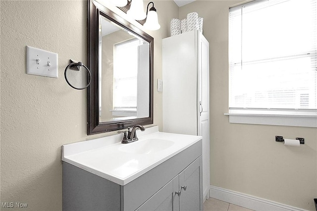 bathroom with a healthy amount of sunlight, tile patterned flooring, baseboards, and vanity