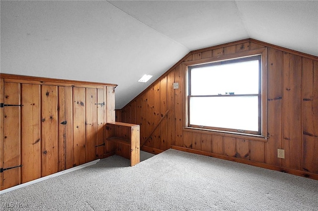 additional living space featuring carpet floors, vaulted ceiling, and wooden walls