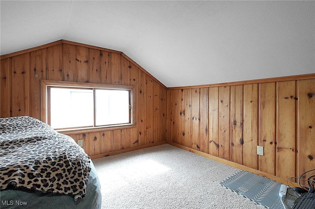 bedroom featuring wooden walls, baseboards, vaulted ceiling, and carpet flooring