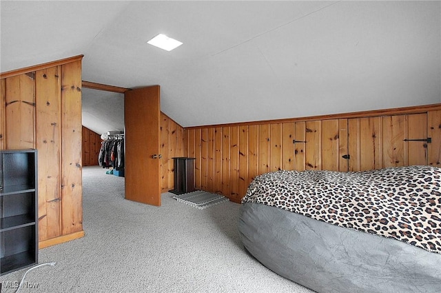 bedroom with vaulted ceiling, wood walls, and carpet flooring