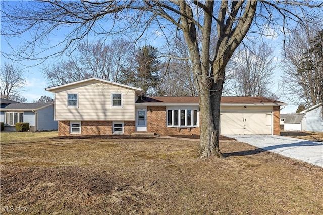 tri-level home featuring an attached garage, a front lawn, concrete driveway, and brick siding