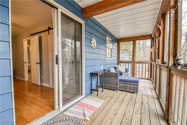 sunroom / solarium featuring a barn door and beam ceiling