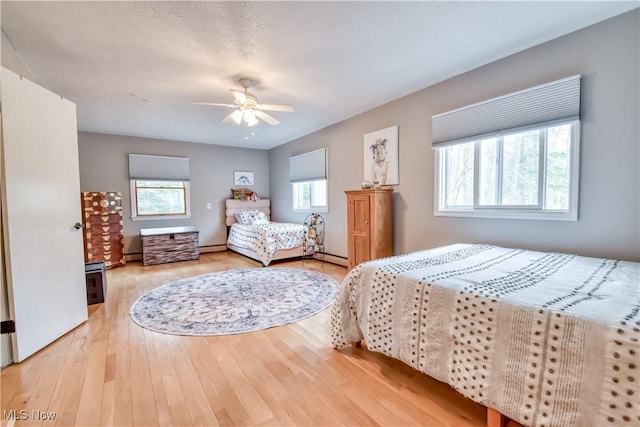 bedroom featuring a baseboard heating unit, hardwood / wood-style flooring, and a ceiling fan