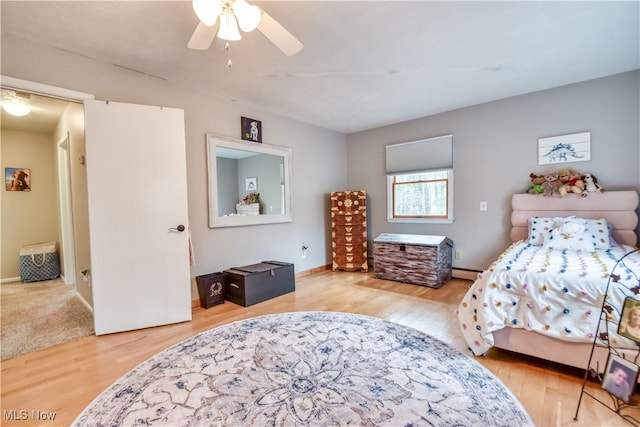 bedroom featuring a ceiling fan, baseboards, baseboard heating, and wood finished floors