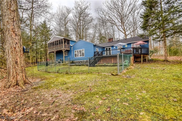 back of property with a deck, a lawn, a chimney, and fence