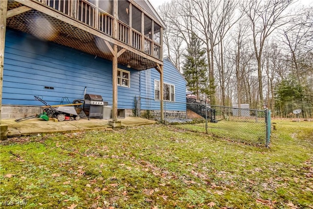 rear view of house with a sunroom, a patio area, a lawn, and fence