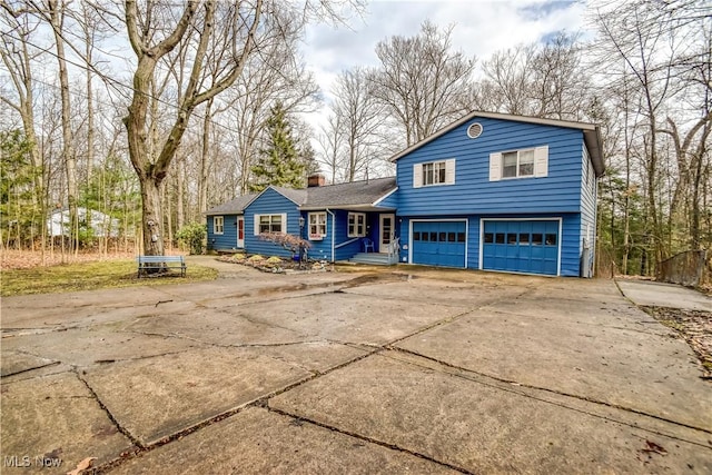 tri-level home with driveway, a chimney, and an attached garage