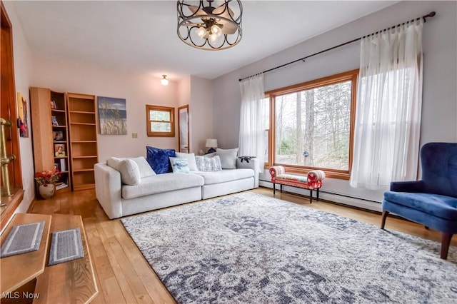 living room with baseboard heating, hardwood / wood-style flooring, and an inviting chandelier