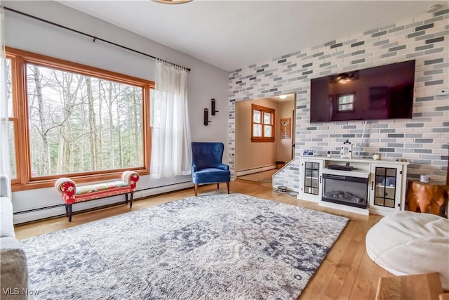 living room with wood finished floors, baseboard heating, and a glass covered fireplace