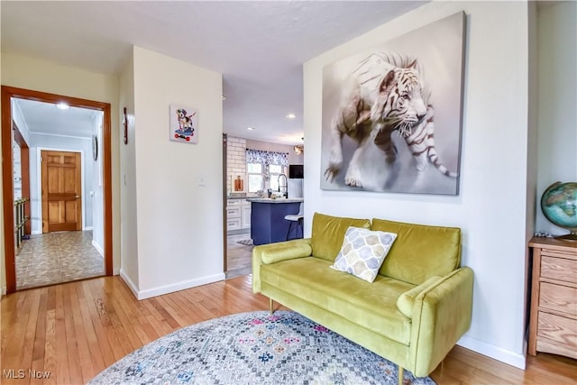 sitting room with baseboards, wood finished floors, and recessed lighting