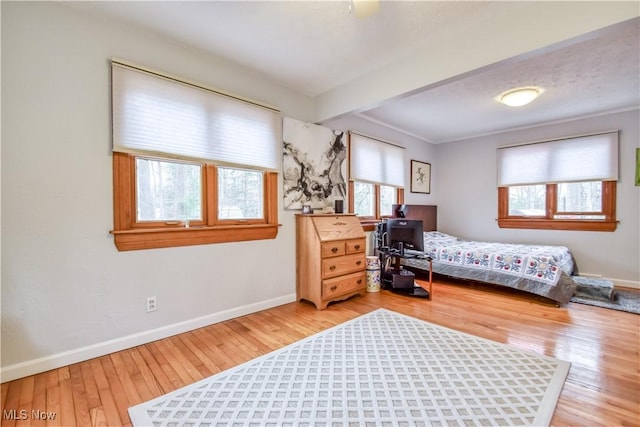 bedroom featuring baseboards, beamed ceiling, and hardwood / wood-style floors