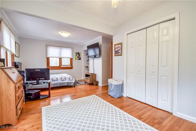 bedroom with light wood finished floors, a closet, and baseboards