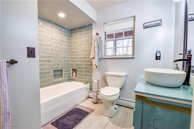 full bathroom with toilet, baseboard heating, wood finished floors, and vanity