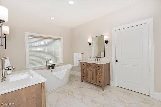 bathroom featuring recessed lighting, vanity, baseboards, a freestanding bath, and marble finish floor