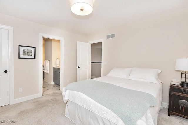 bedroom featuring visible vents, connected bathroom, light carpet, and baseboards