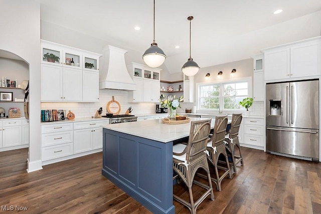 kitchen with premium range hood, white cabinetry, backsplash, a center island, and stainless steel fridge