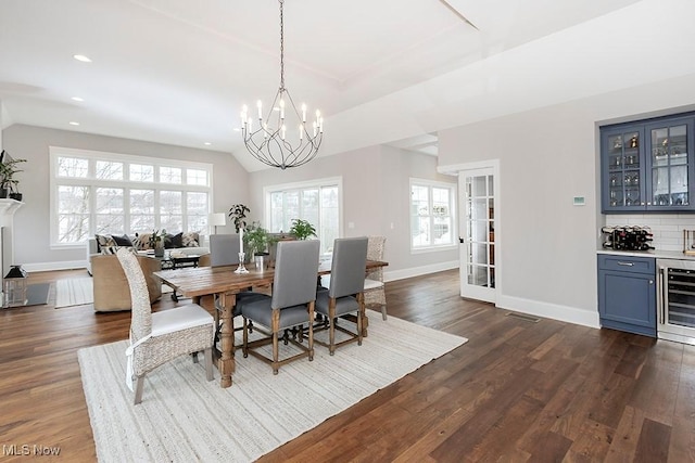 dining space with dark wood-type flooring, wine cooler, lofted ceiling, and a dry bar