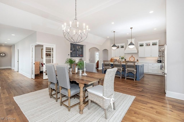 dining space with baseboards, arched walkways, wood finished floors, and recessed lighting