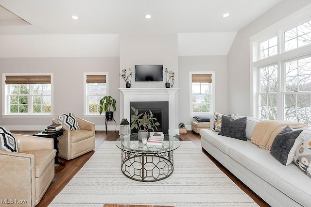 living area featuring a healthy amount of sunlight, a fireplace with flush hearth, dark wood finished floors, and recessed lighting