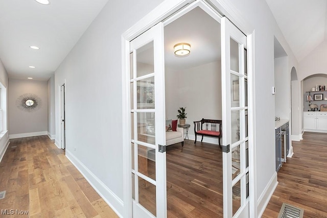 hallway with light wood-type flooring, visible vents, and baseboards