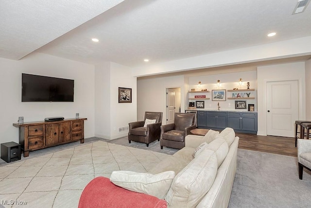 living area featuring baseboards, wet bar, visible vents, and recessed lighting