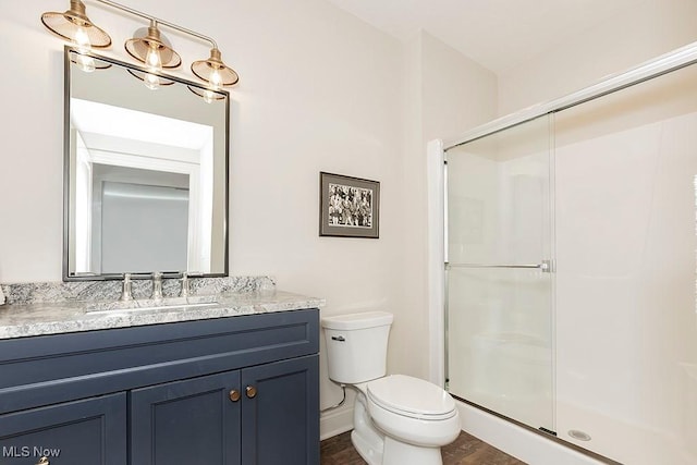 bathroom with a stall shower, vanity, and toilet