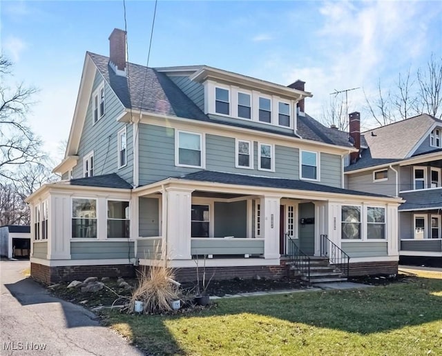 traditional style home with a front yard, covered porch, roof with shingles, and a chimney