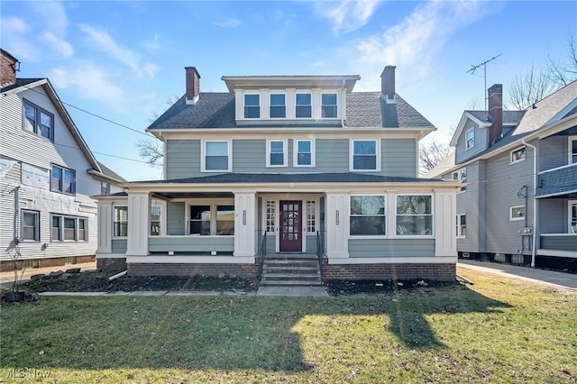 american foursquare style home featuring covered porch, a chimney, and a front lawn