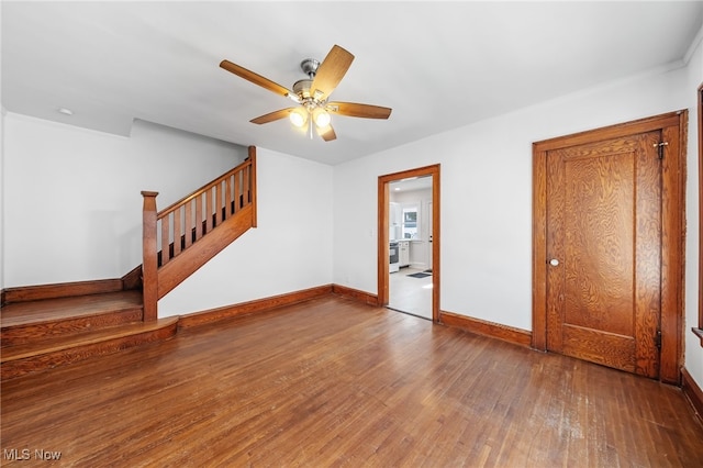 interior space featuring stairs, ceiling fan, wood-type flooring, and baseboards