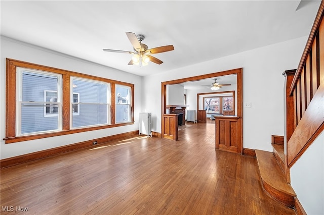 unfurnished room featuring stairs, dark wood-type flooring, baseboards, and radiator