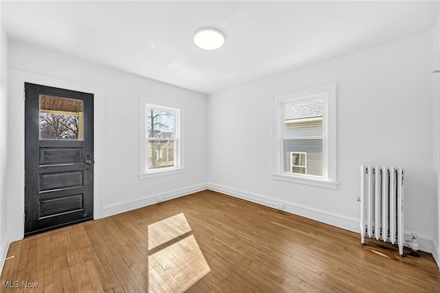 entrance foyer with radiator, wood-type flooring, and baseboards