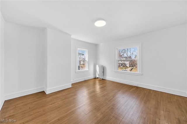 spare room with baseboards, hardwood / wood-style flooring, and radiator