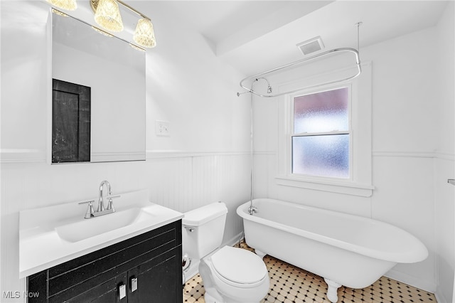 full bath featuring wainscoting, a freestanding bath, vanity, and toilet