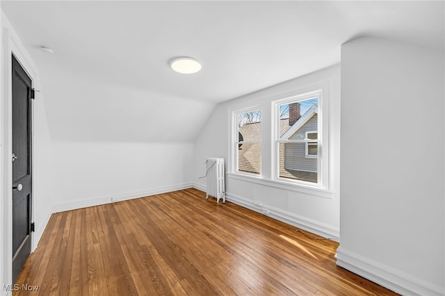 bonus room featuring lofted ceiling, radiator, baseboards, and hardwood / wood-style floors