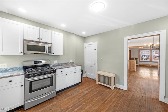 kitchen with stainless steel appliances, white cabinets, baseboards, and dark wood-style floors