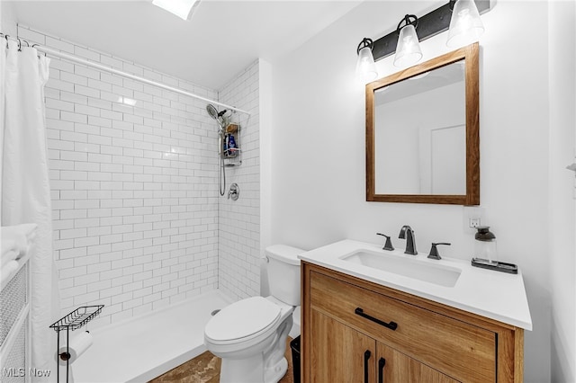 full bathroom with toilet, a tile shower, and vanity