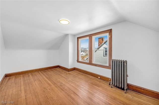 bonus room with baseboards, vaulted ceiling, light wood-style flooring, and radiator heating unit