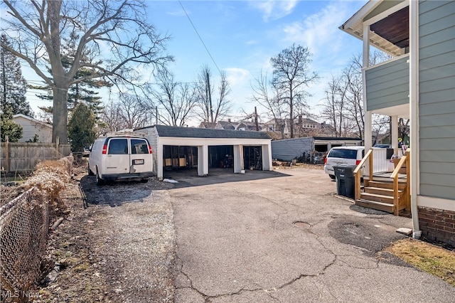 view of car parking featuring a detached garage and fence