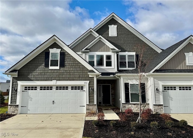 craftsman house featuring a garage, stone siding, board and batten siding, and driveway