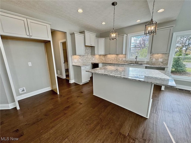 kitchen featuring dark wood-style floors, backsplash, baseboards, and light stone countertops