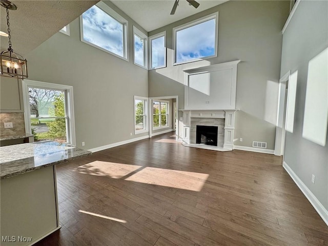 unfurnished living room with dark wood-style floors, baseboards, visible vents, and a high end fireplace