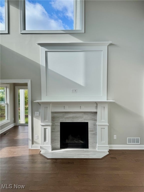 details featuring baseboards, visible vents, wood finished floors, and a tile fireplace